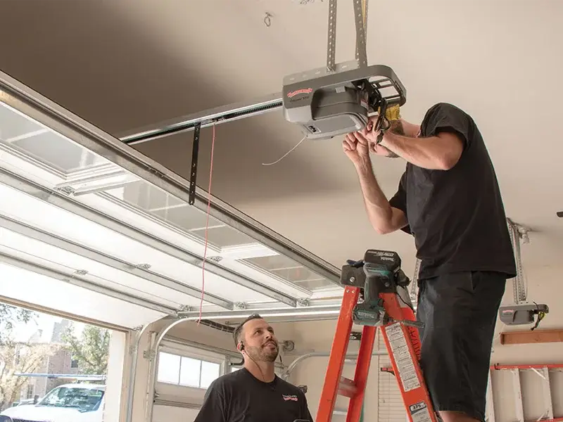 Professional garage door technician performing a tune-up and repair on a garage door system